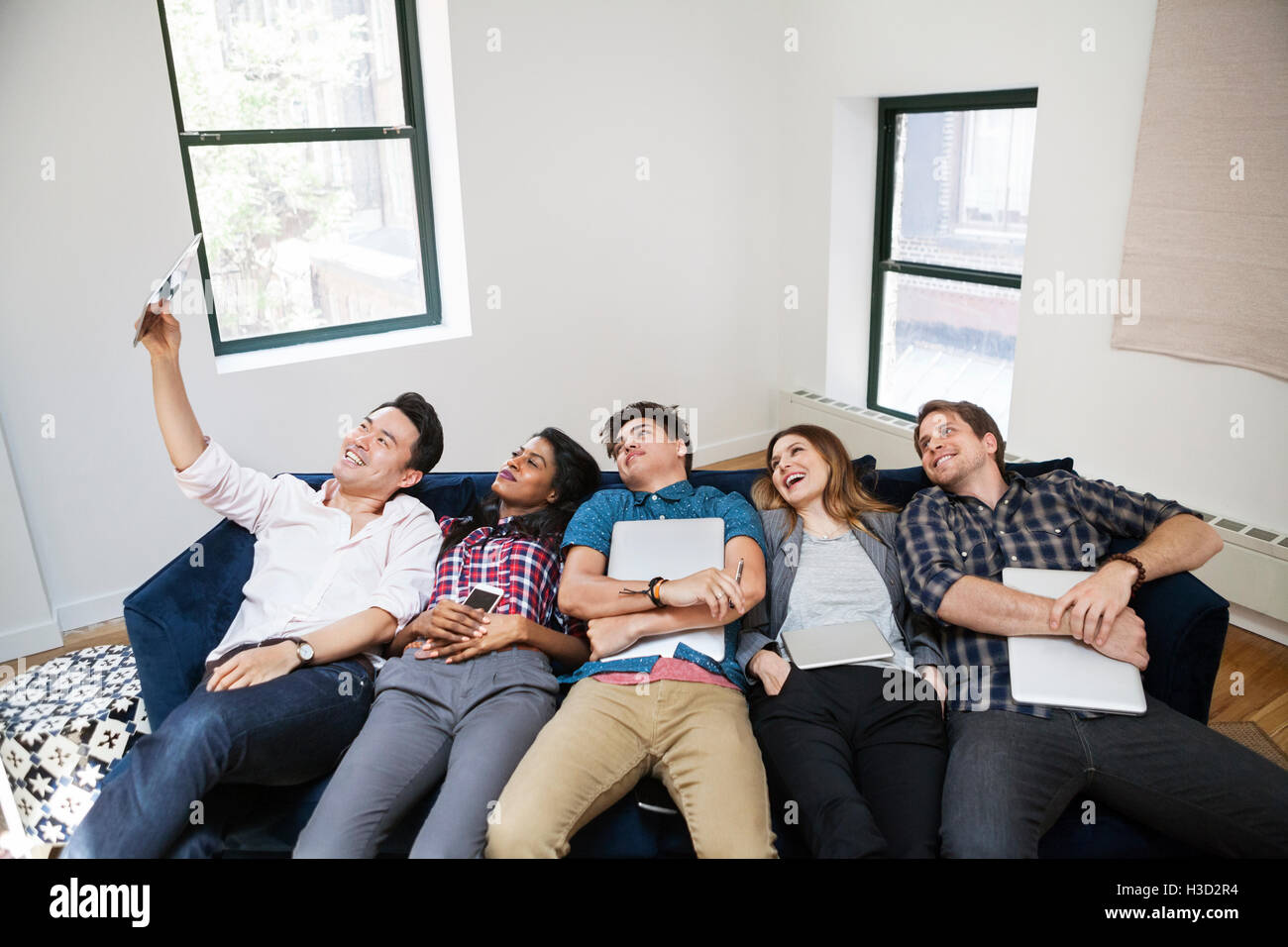 Fröhliche Geschäftsleute nehmen Selfie liegen auf Sofa im Kreativbüro Stockfoto