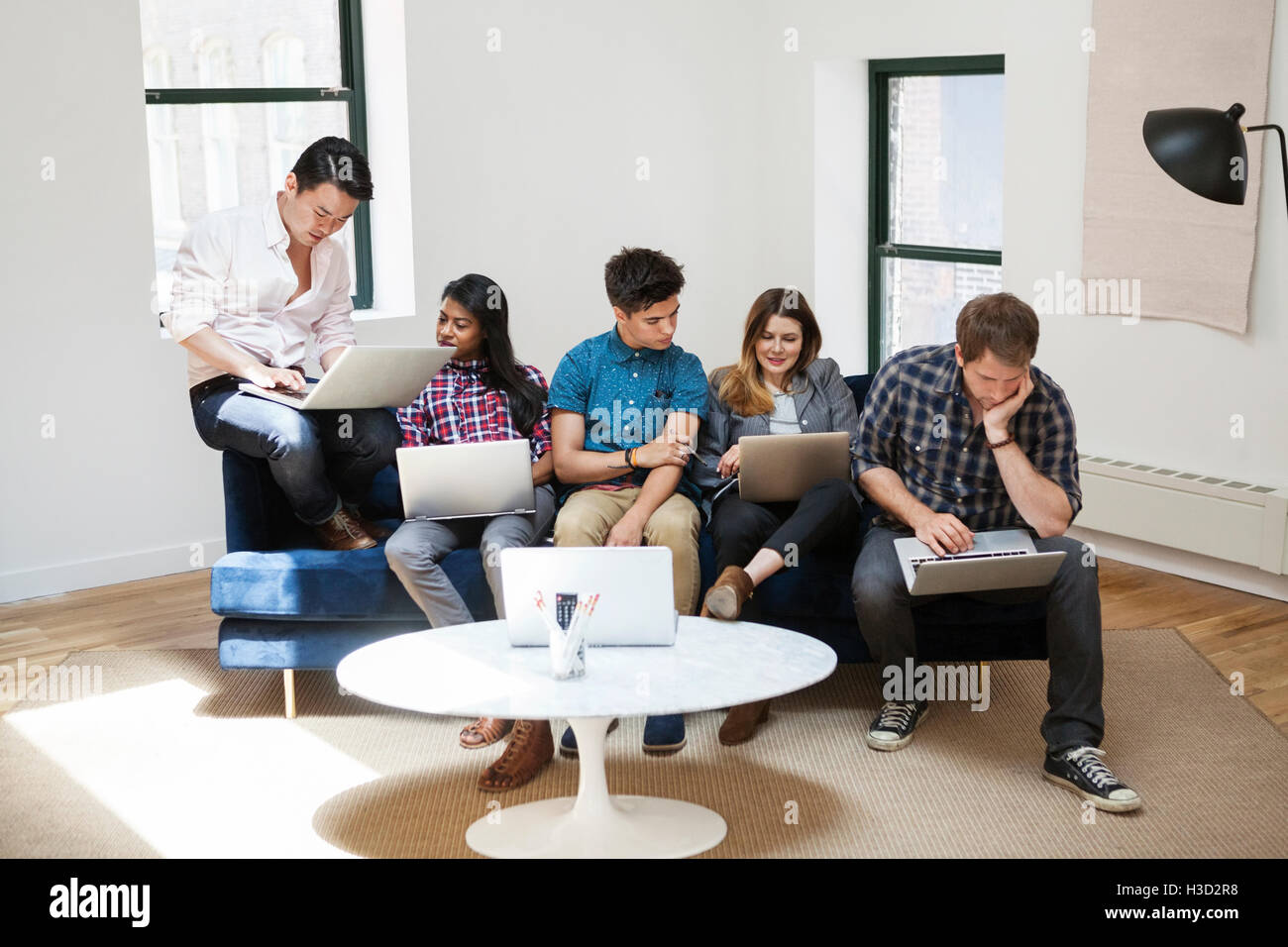 Kolleginnen und Kollegen arbeiten auf Laptops in Kreativbüro Stockfoto