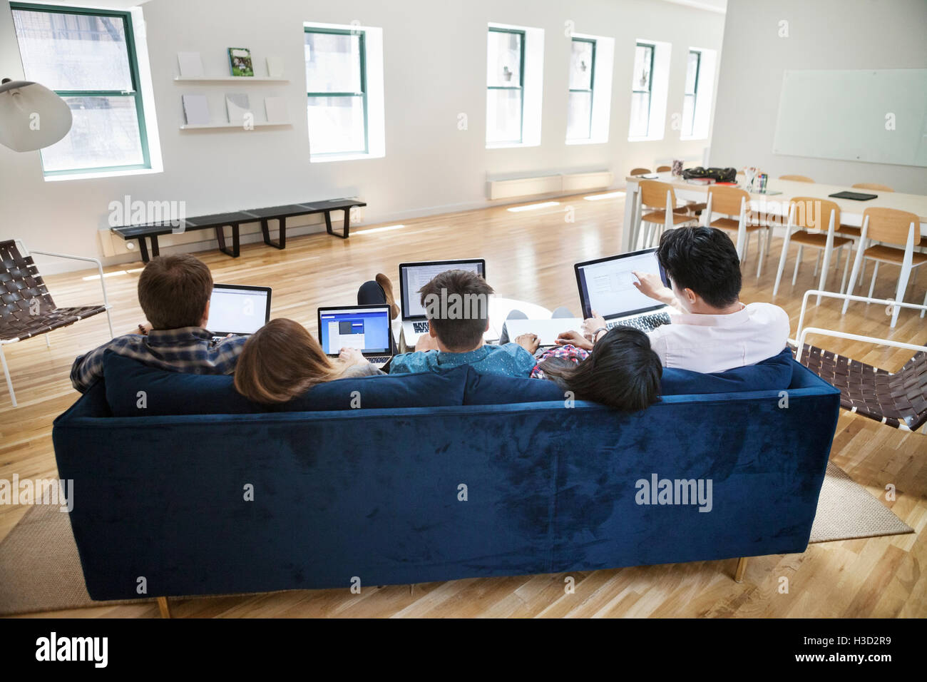 Rückansicht des Business-Leute mit Laptops auf Sofa im Kreativbüro Stockfoto