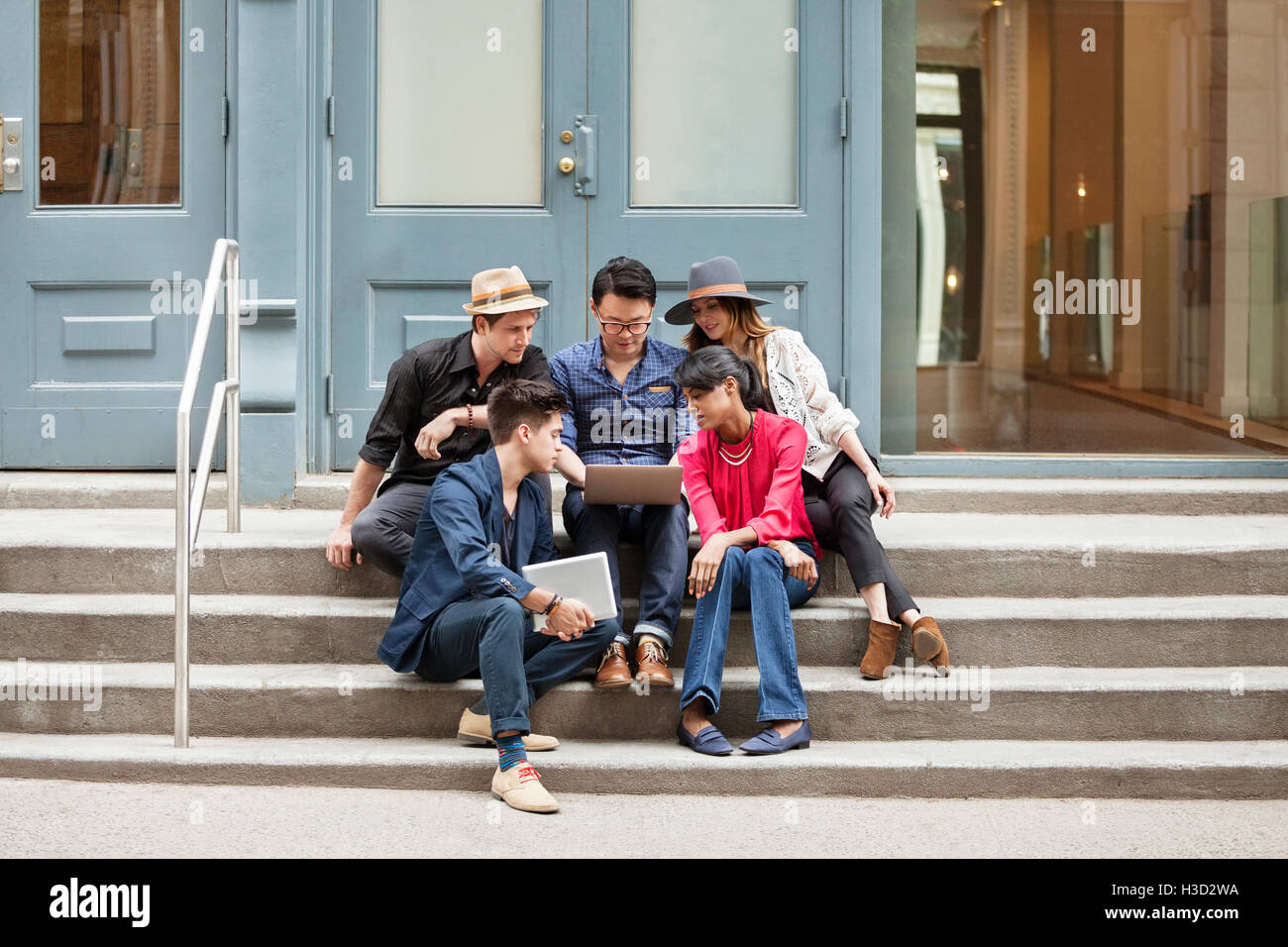 Kreative Geschäftsleute mit Laptop sitzend auf Schritte Stockfoto