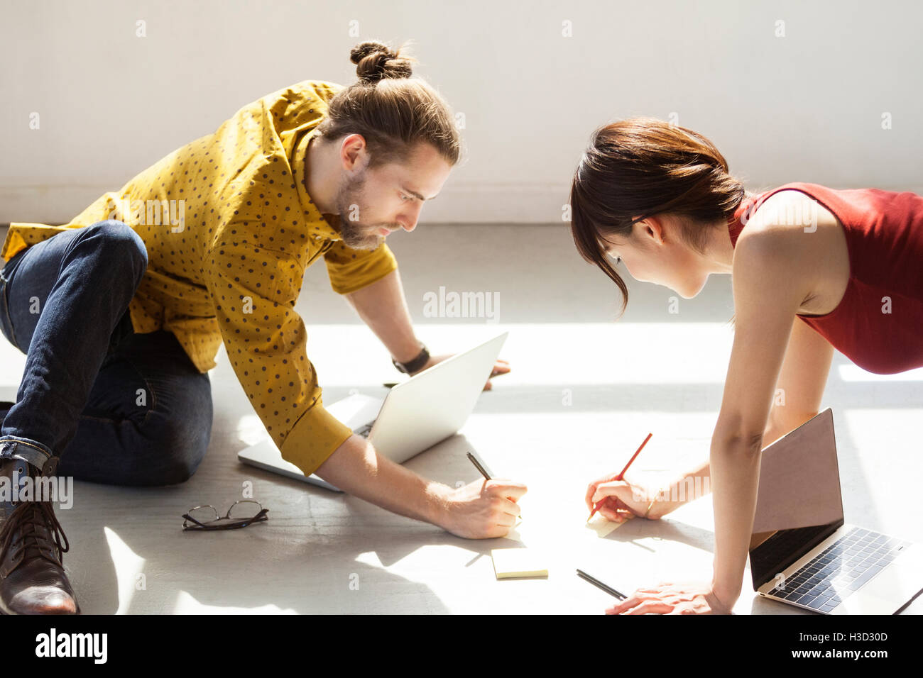 Geschäftsleute schreiben in Notizen auf dem Boden in einem hell beleuchteten Kreativbüro Stockfoto