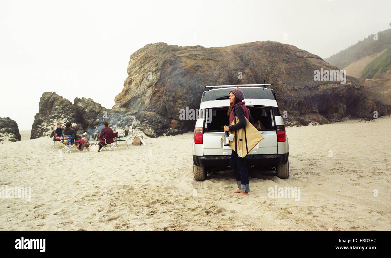 Seitenansicht der Frau Tragetasche mit dem Auto am Strand Stockfoto
