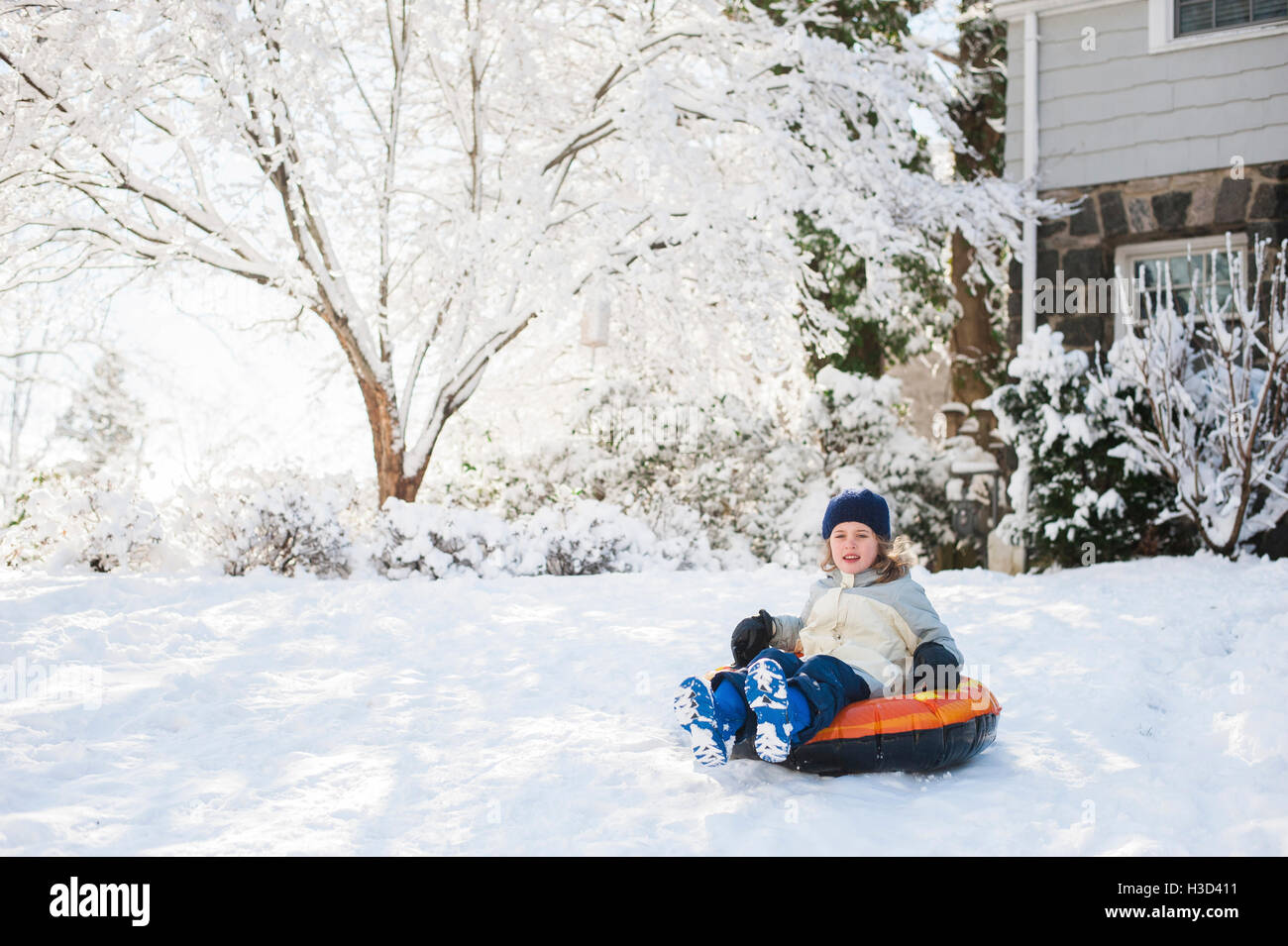 Glückliches Mädchen sitzen auf aufblasbaren Ring im Hinterhof im winter Stockfoto
