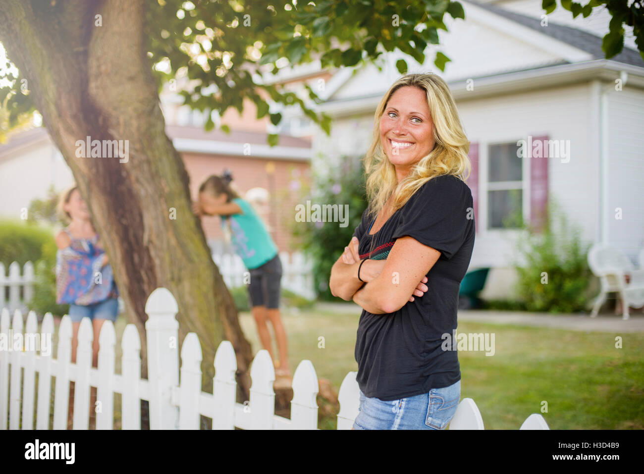 Glückliche Frau wegsehen, während die Kinder spielen verstecken und suchen im Hinterhof Stockfoto