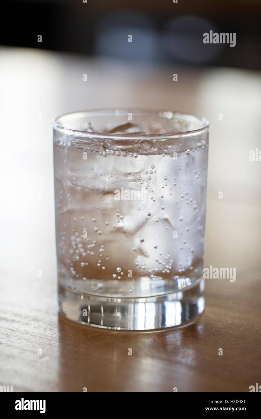 Nahaufnahme von kohlensäurehaltigem Wasser im Glas auf Holztisch Stockfoto