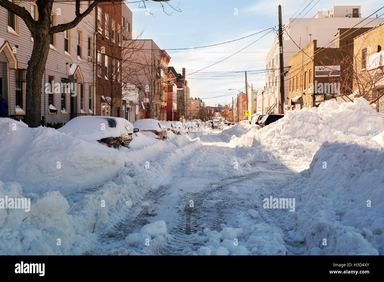 Autos auf Schnee bedeckt Straße inmitten von Gebäuden in der Stadt Stockfoto
