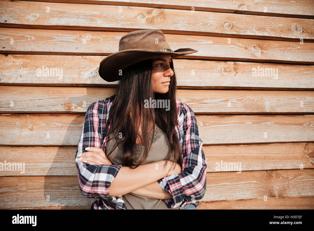Schöne junge Frau Cowgirl Hut Ruf mit Arme gekreuzt auf hölzernen Hintergrund Stockfoto
