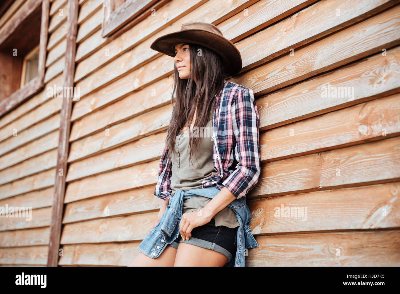 Porträt von attraktiven jungen Womna Cowgirl in Hut Stand in der Nähe des Hauses Stockfoto