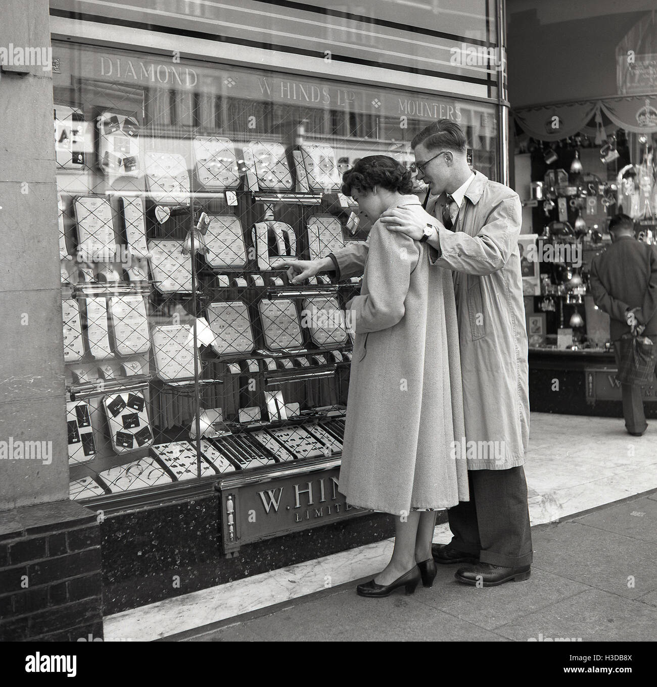 der 1950er Jahre, historisch, studieren romantisch zu zweit die Ringe in einem Schaufenster von W. Hinds Ltd, einem Juwelier in London, England. Stockfoto