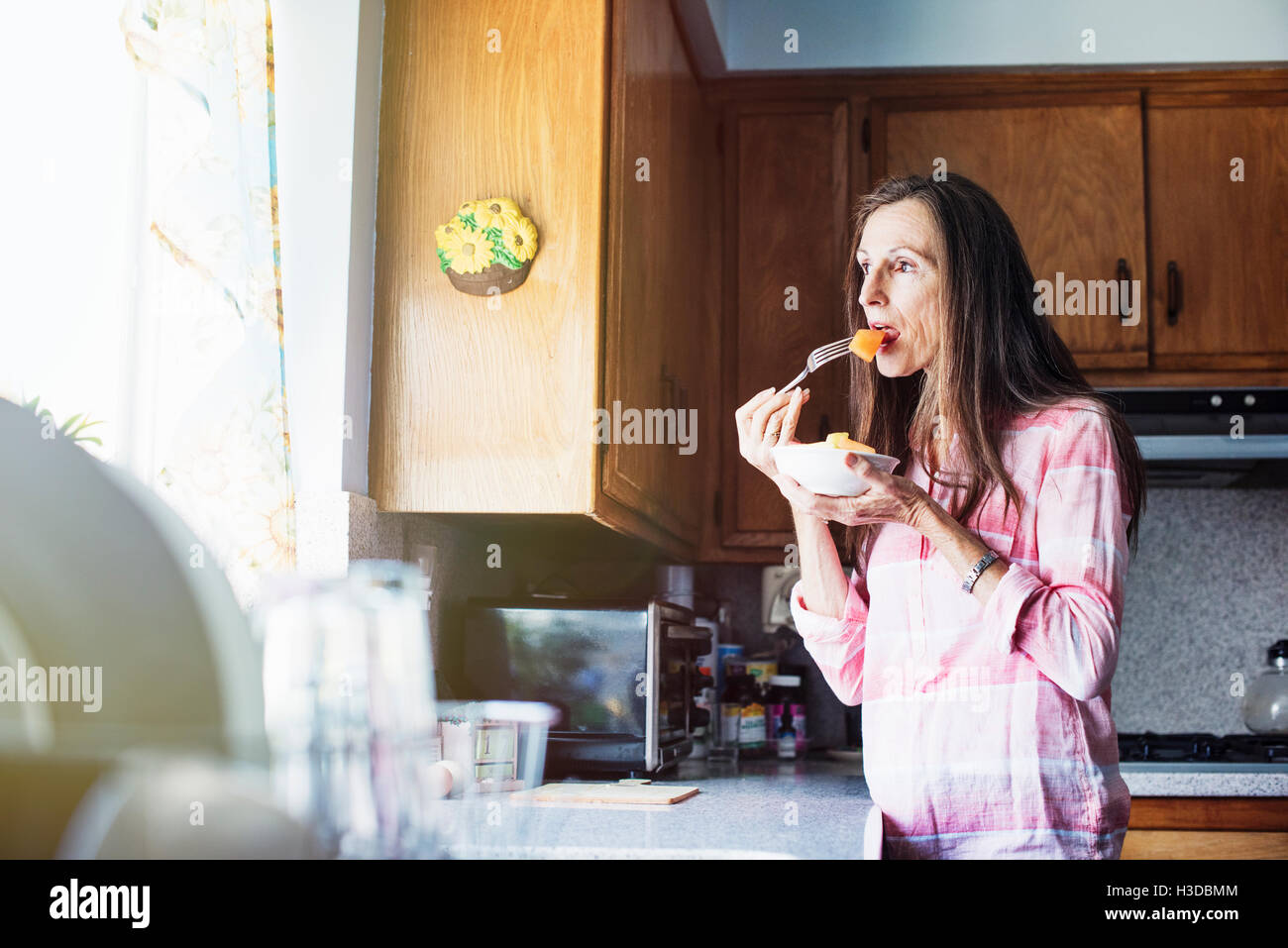 Ältere Frau in der Küche stehen, Essen. Stockfoto