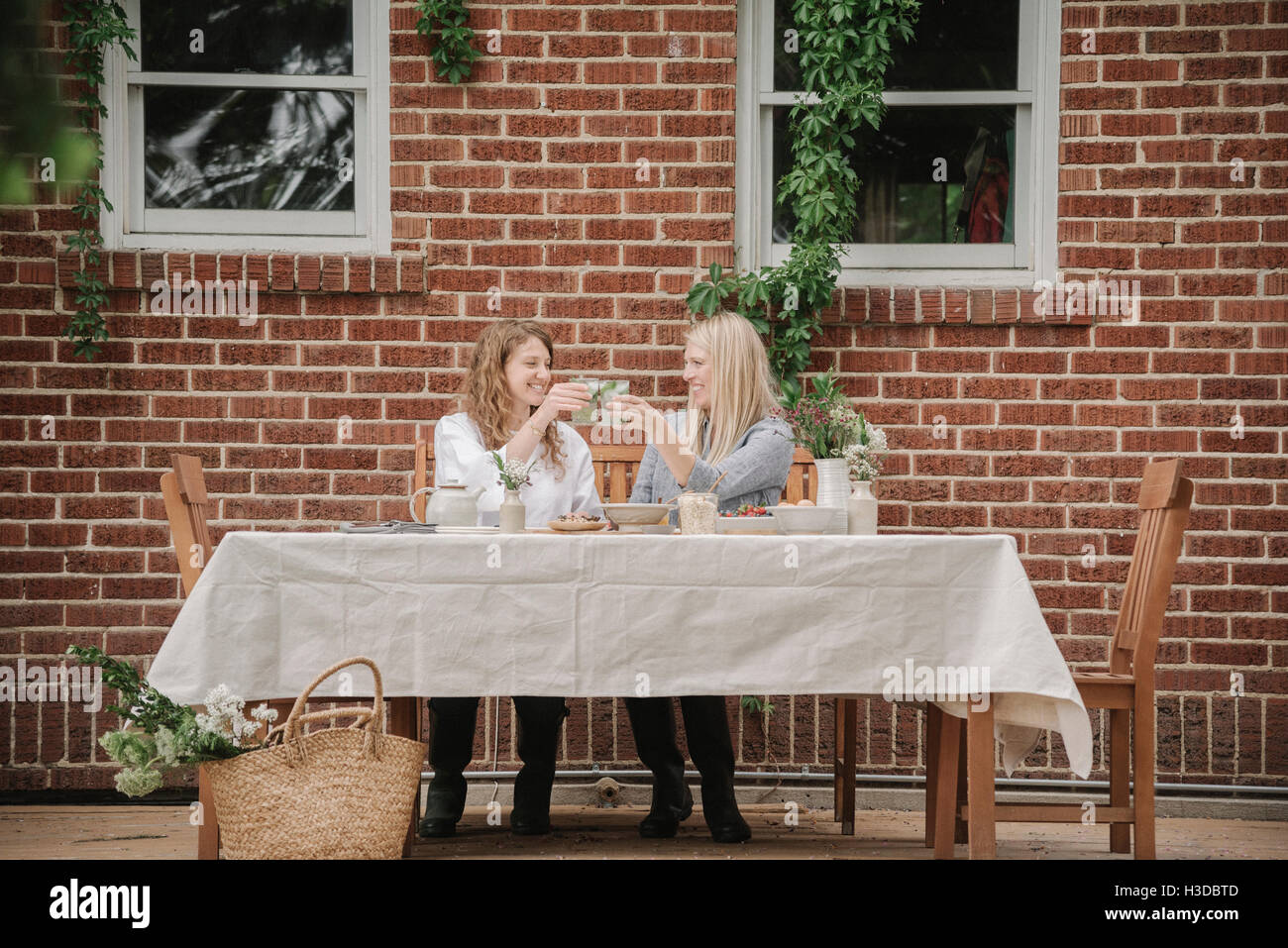 Zwei Frauen sitzen vor einem Haus mit einer Mahlzeit. Stockfoto