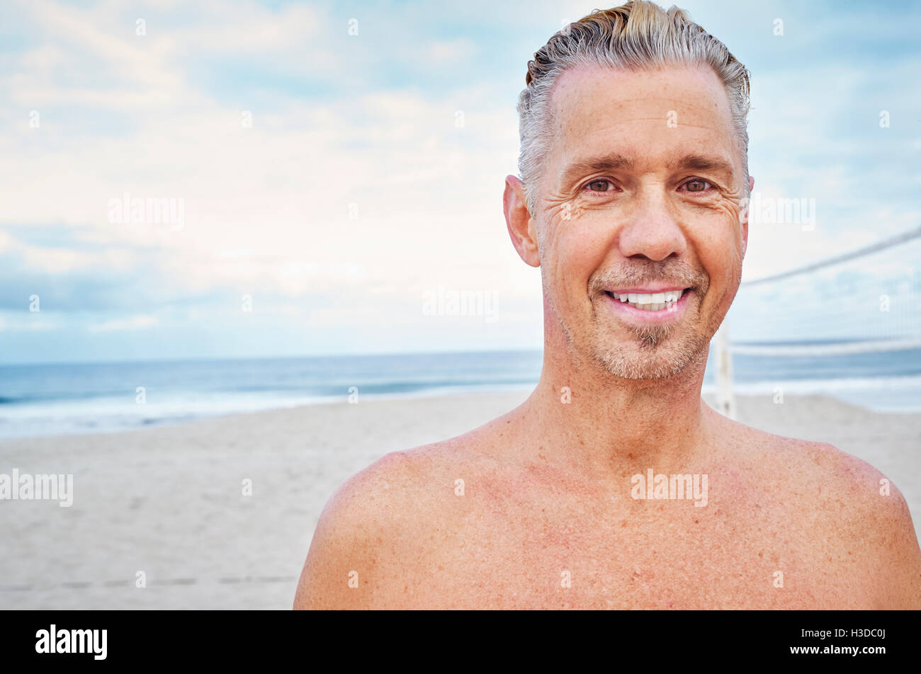 Reifer Mann steht am Strand, in die Kamera Lächeln. Stockfoto
