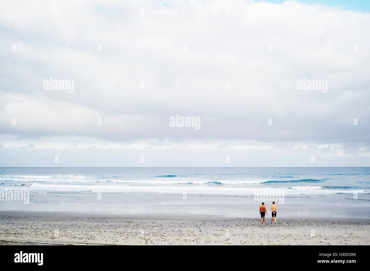 Zwei Männer stehen an einem Sandstrand am Meer. Stockfoto