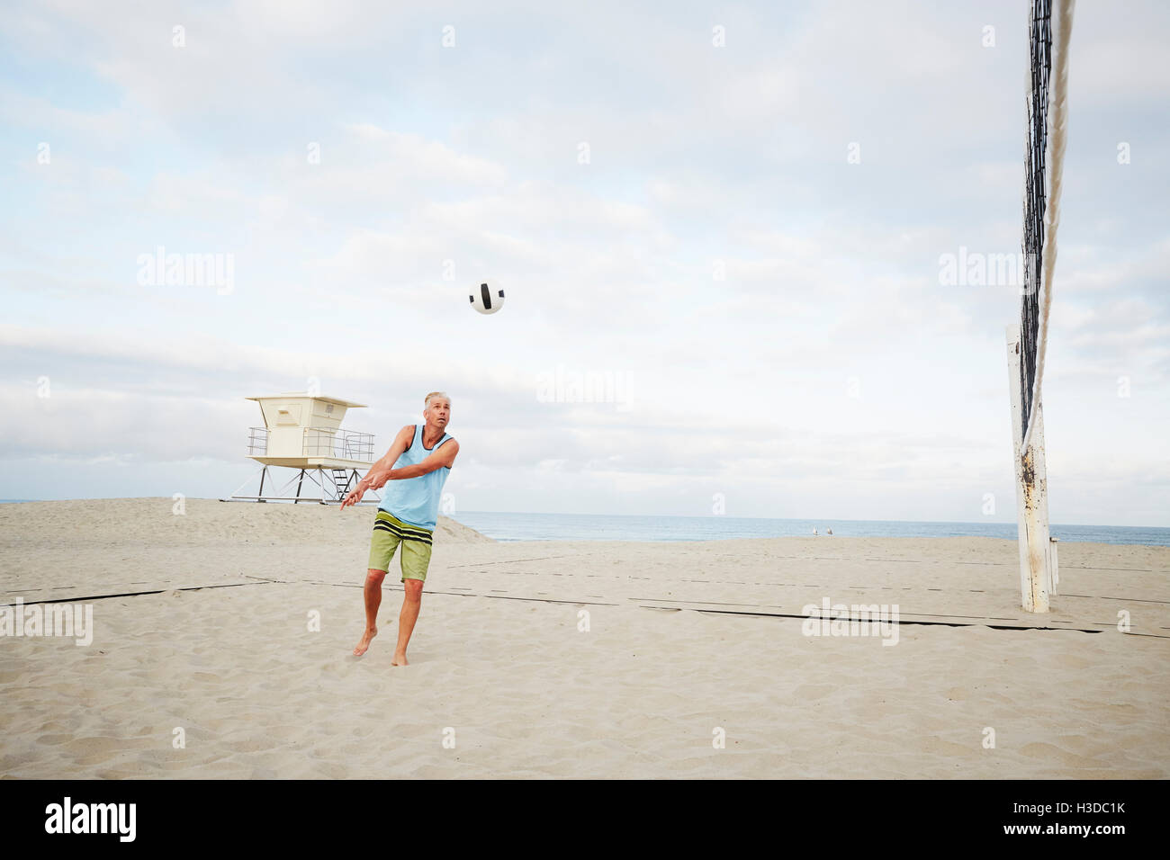 Reifer Mann stehend an einem Strand, Beach-Volleyball zu spielen. Stockfoto