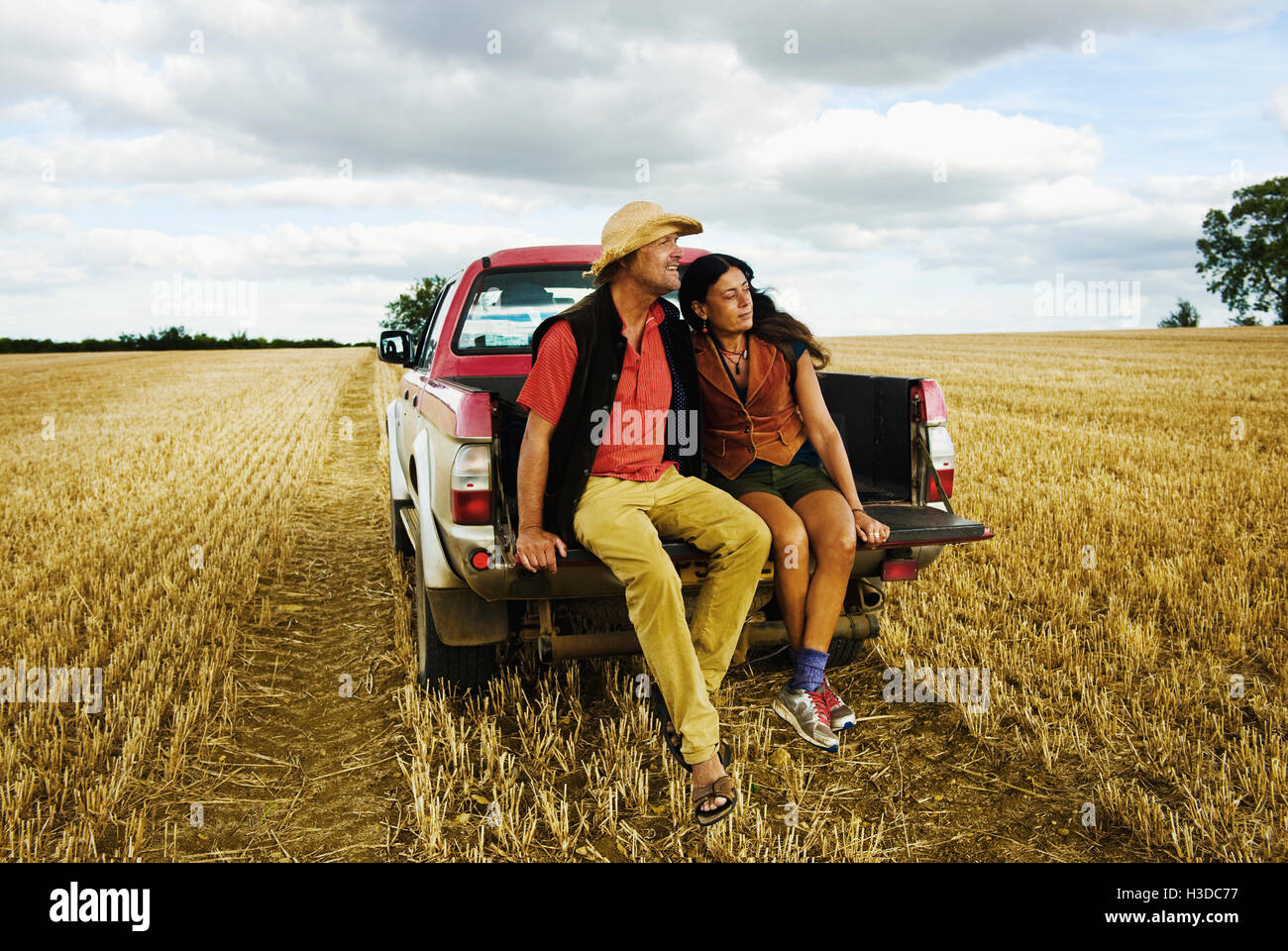 Ein Mann in einem Strohhut und eine Frau sitzen im hinteren Teil ein Pick up Truck. Stockfoto