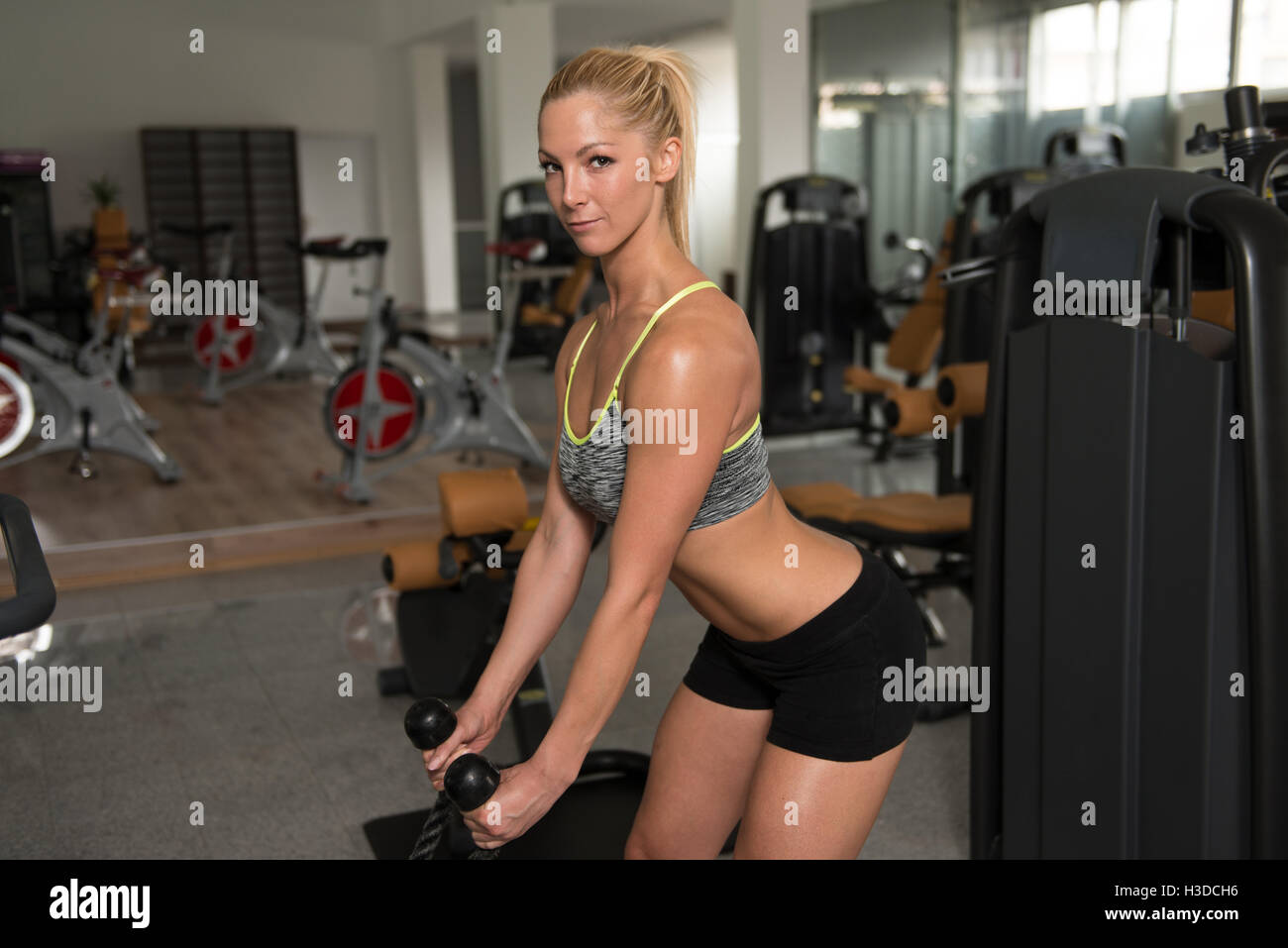 Junge gesunde Fitness Frau schwere Übung für Bizeps Maschine In der Turnhalle Stockfoto