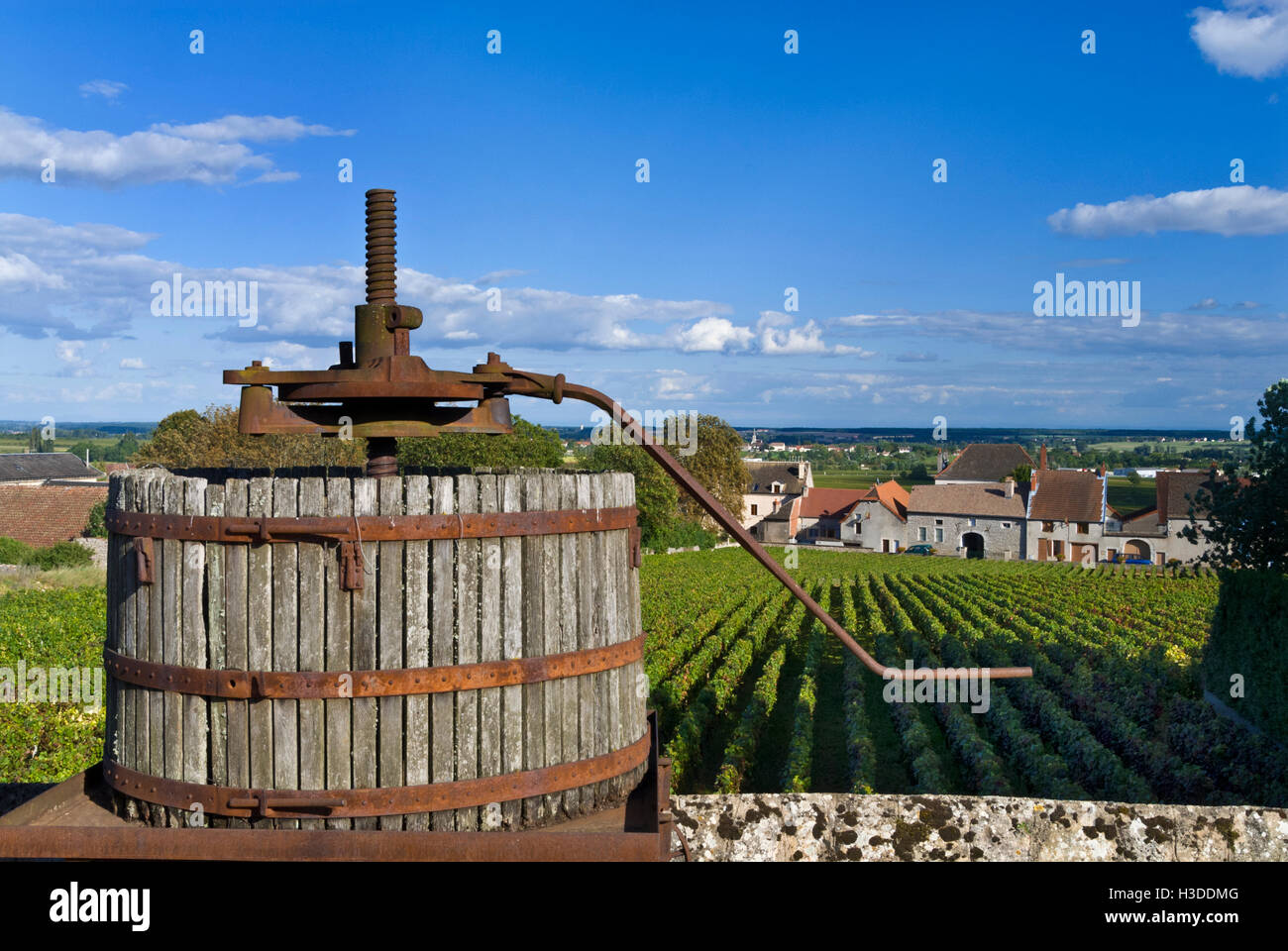 Alte hölzerne Weinpresse mit premier Cru Weinbergen und Dorf von Chassagne Montrachet, Burgund, Côte d ' or. Frankreich Stockfoto
