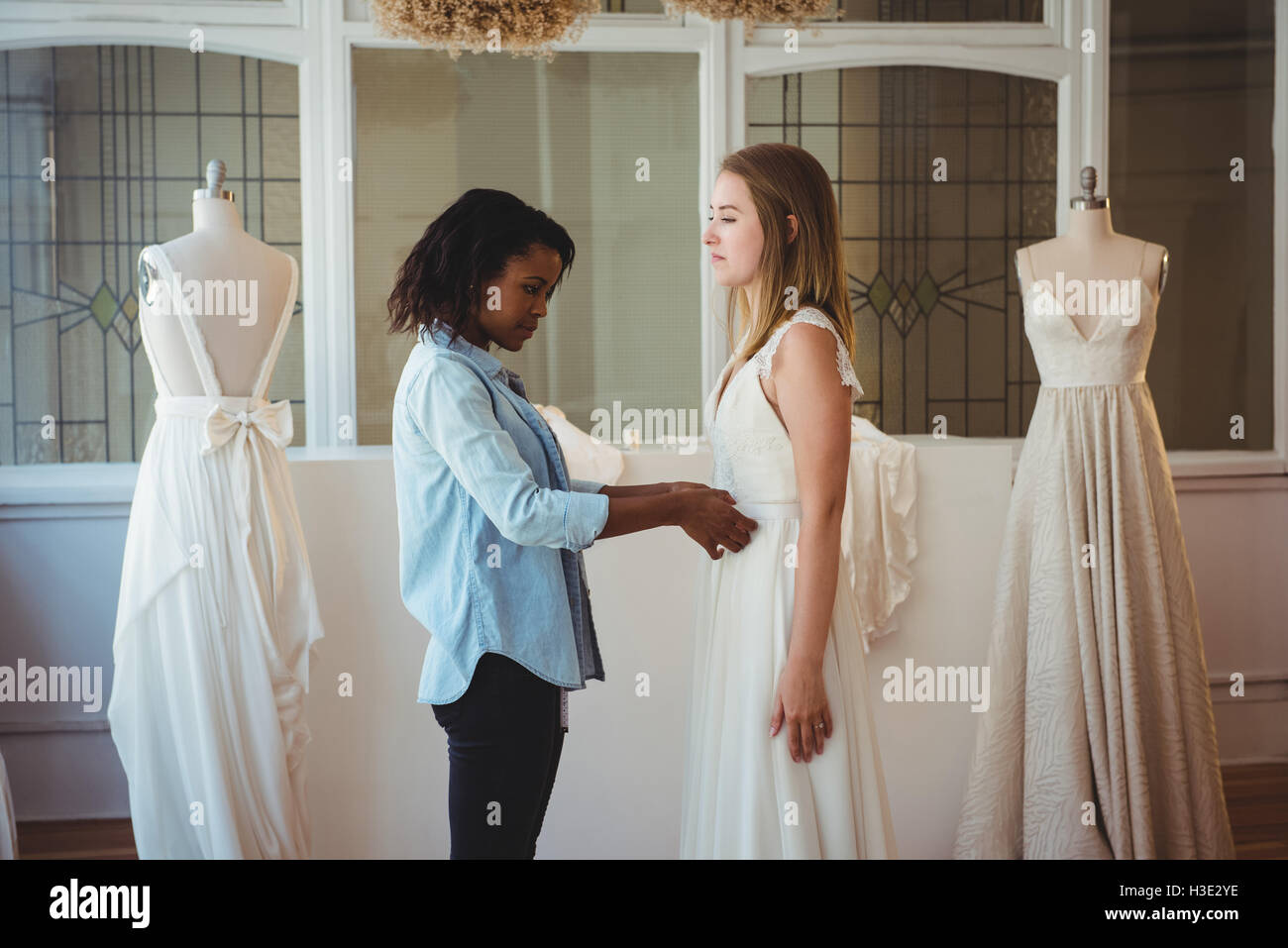Frau versucht auf Hochzeitskleid mit Hilfe der Mode-designer Stockfoto