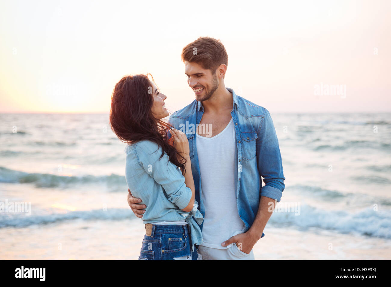 Glückliches junges Paar Lachen und umarmt am Strand Stockfoto