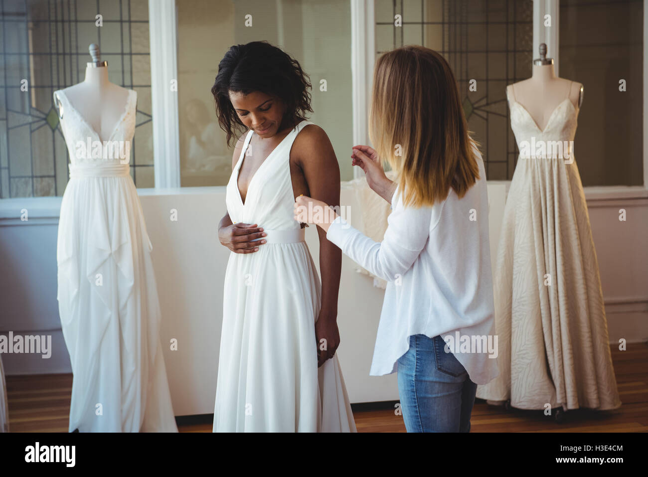 Frau versucht auf Hochzeitskleid mit Hilfe der Mode-designer Stockfoto