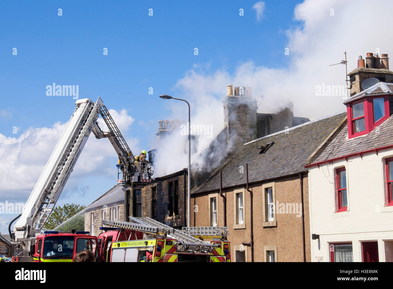 Schottische Feuerwehr Feuerwehr oben eine Leiter, die Bewältigung einer brennenden Hausdach. Elie und Earlsferry Fife Schottland UK Stockfoto