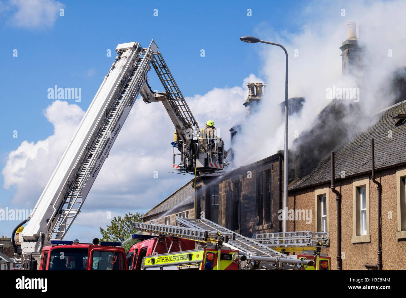 Schottische Feuerwehr Feuerwehr oben eine Leiter, die Bewältigung einer lodernden Hausdach. Elie und Earlsferry Fife Schottland UK Stockfoto