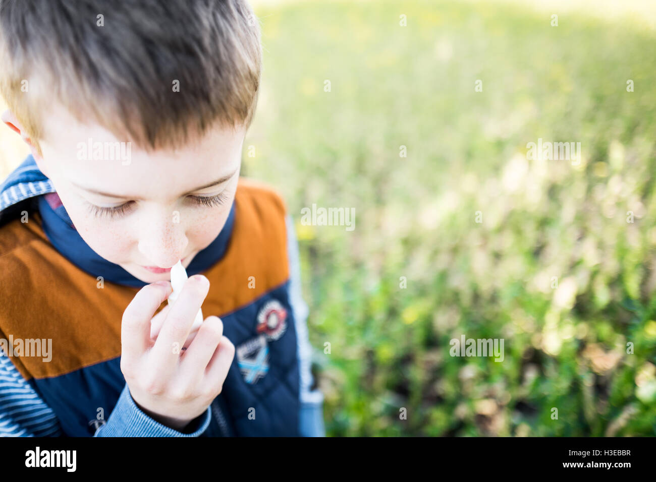 Close Up eines kleinen Jungen mit einem Nasenspray und Pollenallergie leiden. Stockfoto