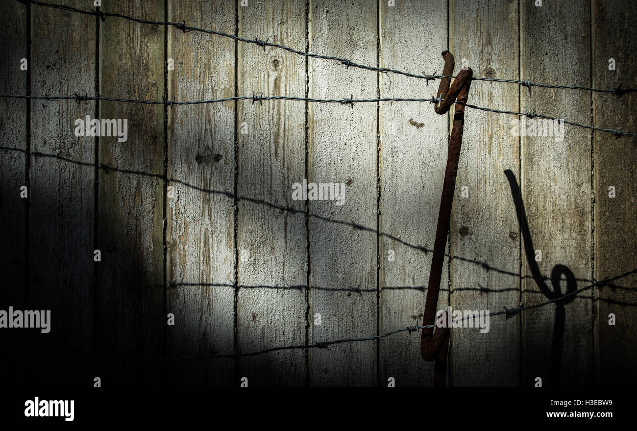 Stränge von einem Stacheldrahtzaun und Unterstützung von WWI Tage gegen die verblichenen Planken einer alten Holzzaun mit bedrohlichen Schatten Stockfoto