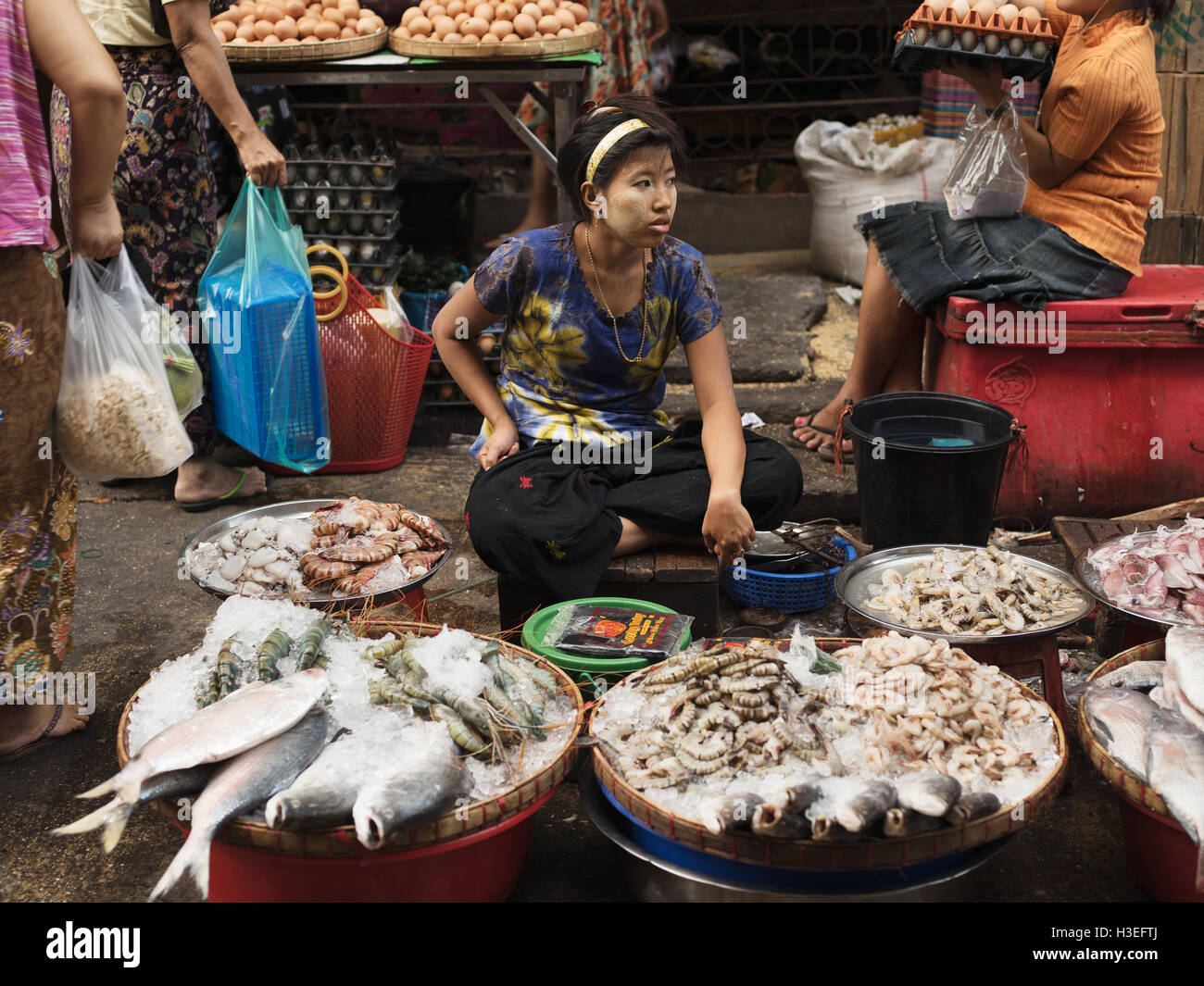 Eine Myanmarese Frau verkauft Fisch auf dem Markt. Die gelbe Paste im Gesicht heißt Thanaka und ist traditionell in ihrer Kultur Stockfoto
