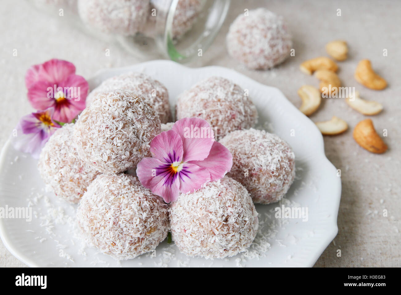 Hausgemachte Erdbeer, Datum, Cashew und Kokosnuss Glückseligkeit Ball mit essbaren Blüten Stockfoto