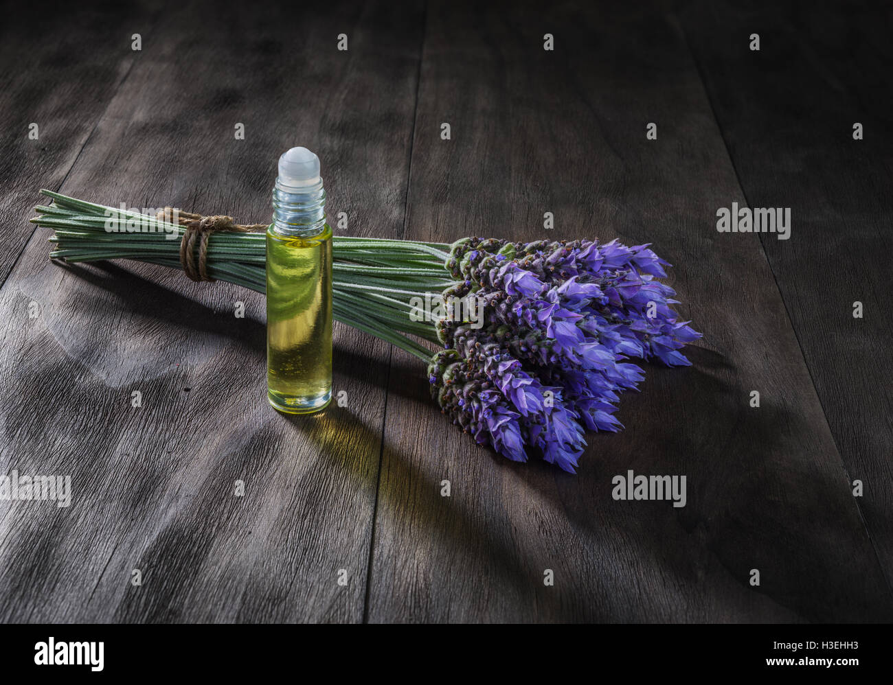 frische Lavendelblüten und ätherische Öle als natürliche Aromatherapie für Kopfschmerzen und Migräne Relief auf alten hölzernen Hintergrund Stockfoto