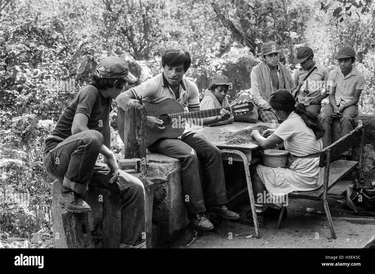 CHALATENANGO, EL SALVADOR, FEB 1984: - innerhalb der FPL Guerilla Zonen der Steuerung Teenager und junge Burschen, die Versorgung in der Nacht auf See-Cuscatlan Fähre Gitarrenmusik zu hören. Stockfoto