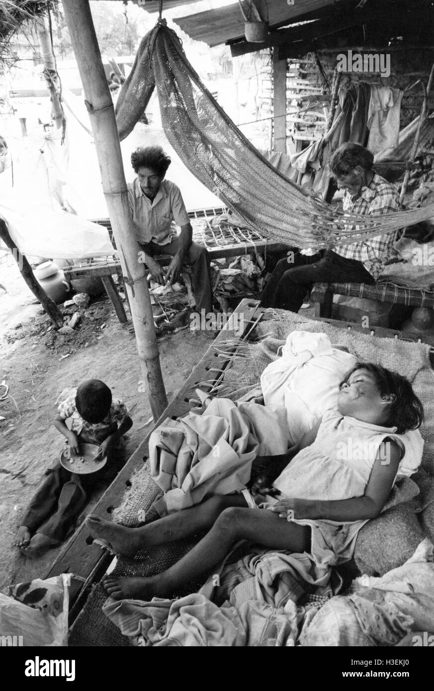 SAN Vicente, EL SALVADOR, März 1982: schläft ein Kind und Erwachsene vertreiben uns die Zeit in einem Lager für Vertriebene in San Vincente. Stockfoto