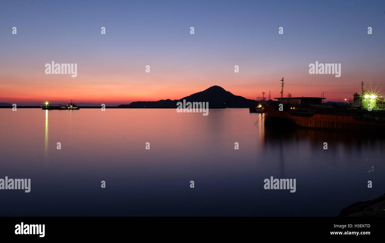 Schöner Sonnenaufgang mit einem kleinen Berg und Schiff Stockfoto