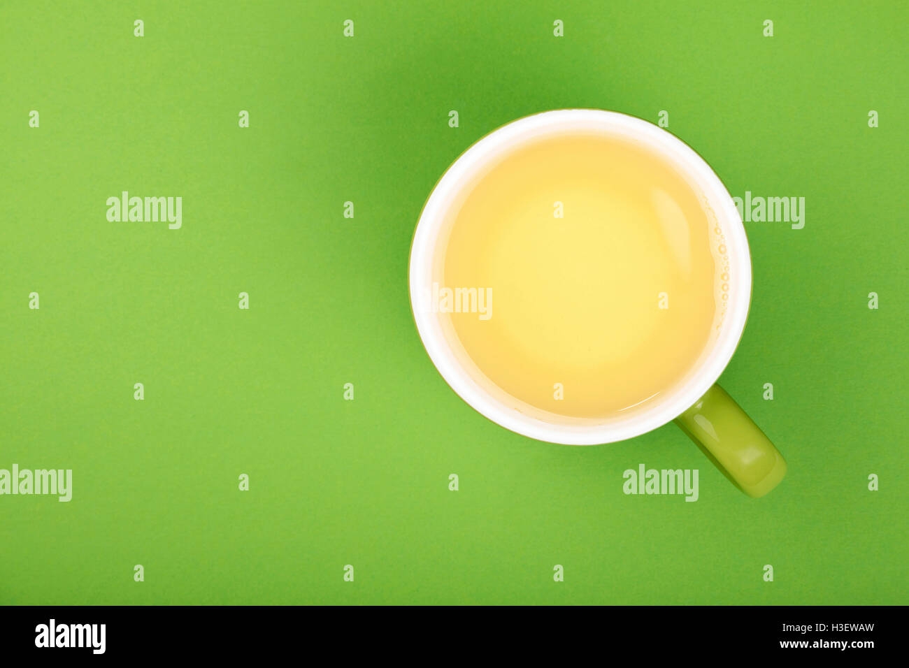 Eine volle gebraut frisch deutlich grüner Oolong Tee in großen Tasse mit Untertasse auf grünem Papierhintergrund, Draufsicht, Vogelperspektive Stockfoto