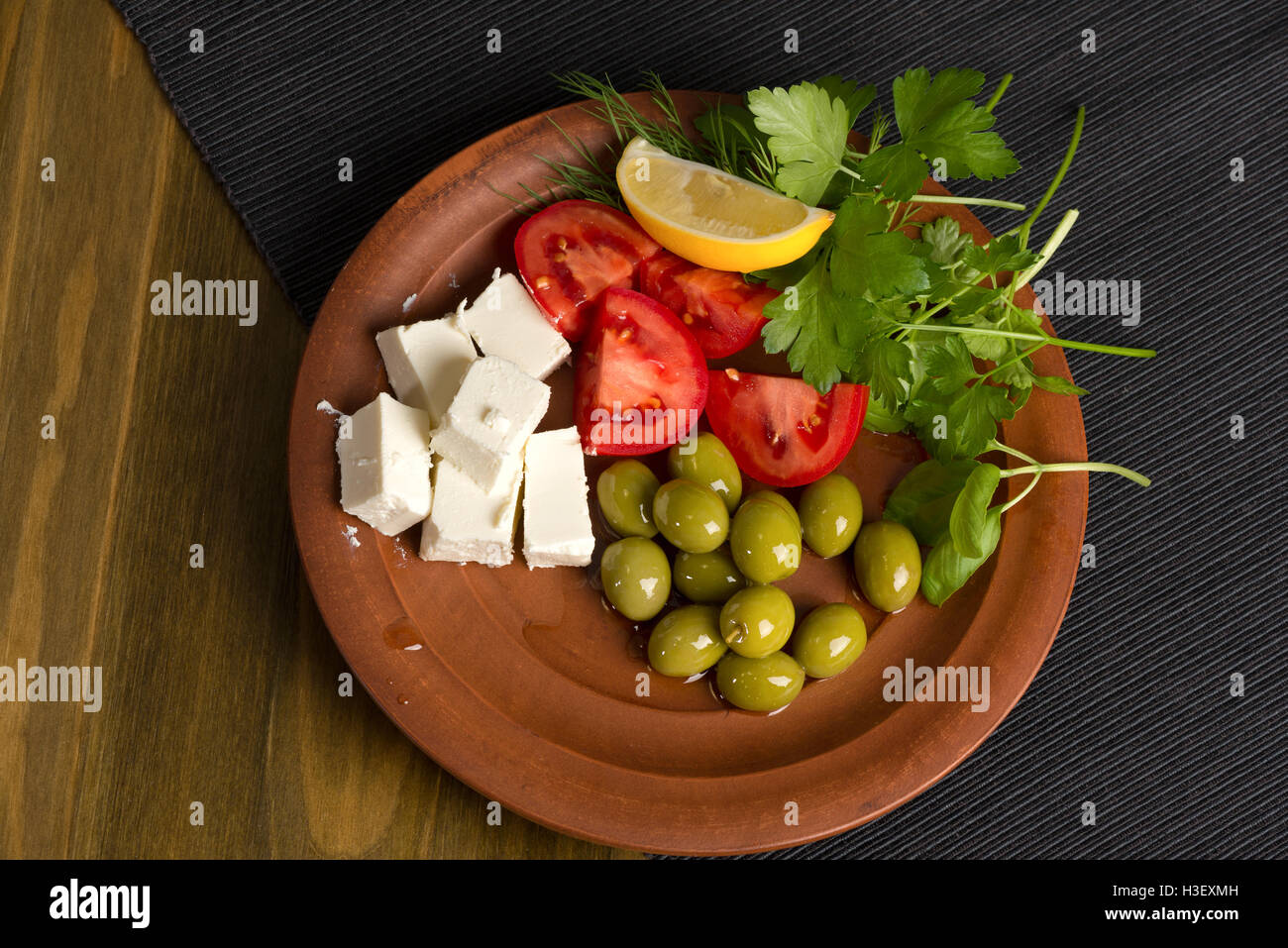 Feta-Käse, Tomaten, Oliven und Kräutern in einer Ton-Platte - griechischen Mittagessen Stockfoto