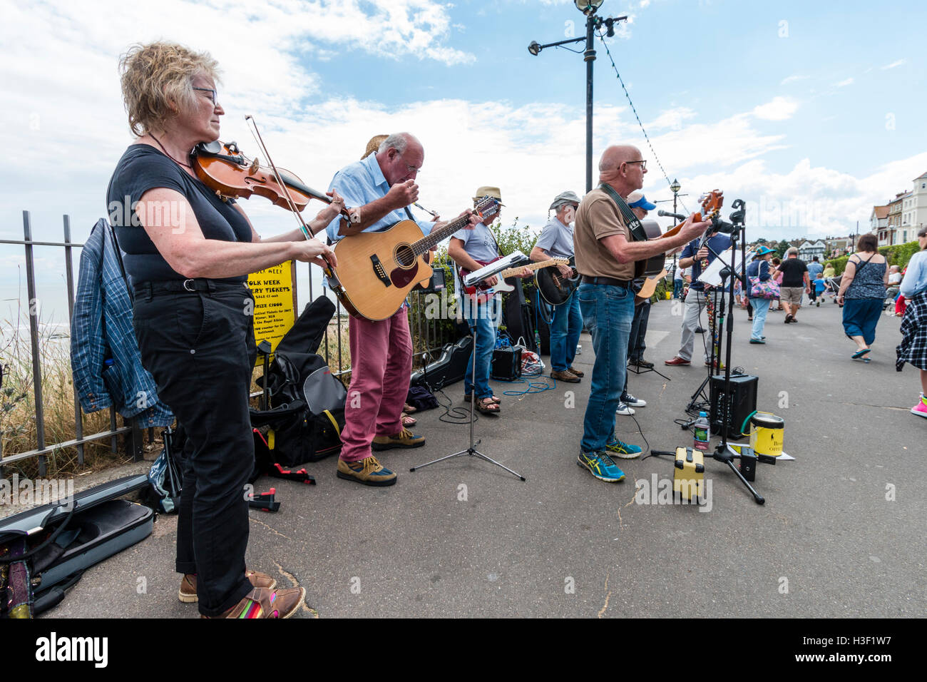 Die Bucht Jungs, Musical folk Gruppe der älteren Männer Gitarren spielen im Sonnenschein, zusammen mit einer Frau Fiddle Player führen Sie ein Konzert auf der Strandpromenade. Stockfoto