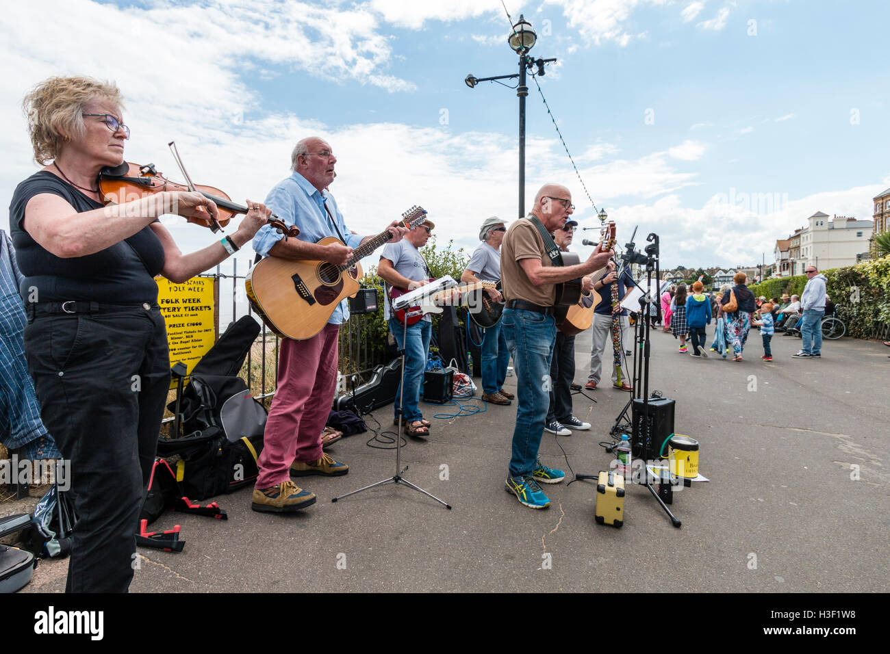 Die Bucht Jungs, Musical folk Gruppe der älteren Männer Gitarren spielen im Sonnenschein, zusammen mit einer Frau Fiddle Player führen Sie ein Konzert auf der Strandpromenade. Stockfoto