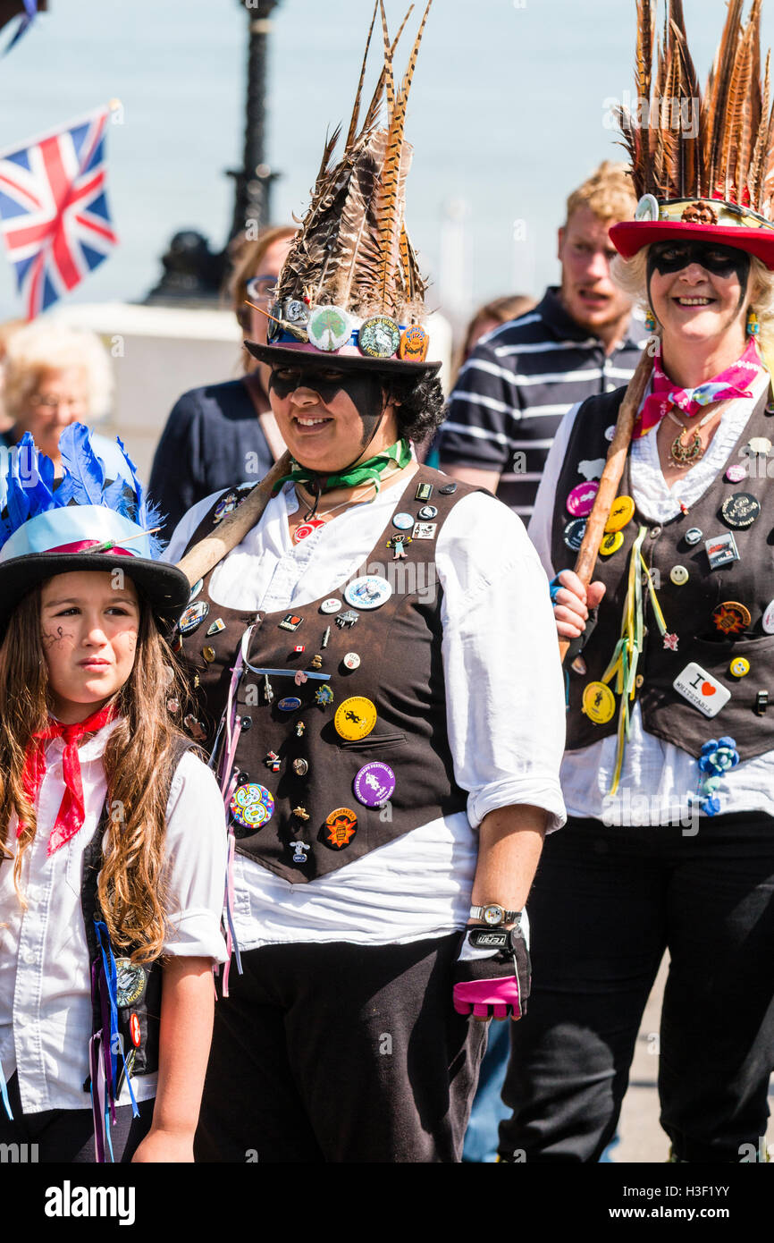 Broadstairs Folk Woche Festival. Dead Horse Morris und Broomdashers, zwei Frauen und Kind, lächelnd zu Fuß im Einklang mit Pfosten ruht auf den Schultern Stockfoto