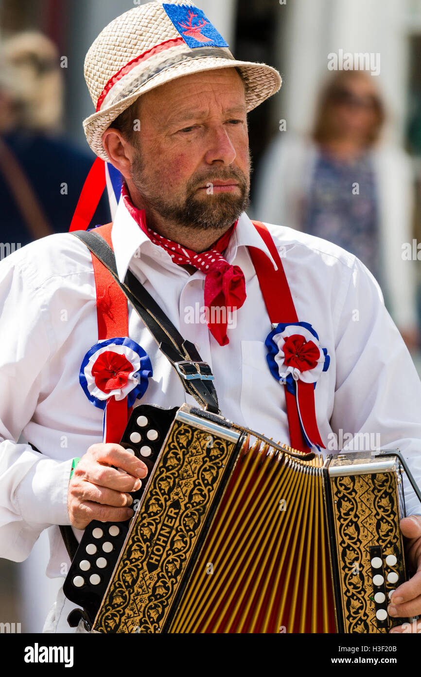 Traditioneller Folk Musiker, Mann mit Strohhut, Mitglied von Hartley Morris Seite, spielen auf dem Akkordeon mit Paar aus Fokus Menschen hinter, Stockfoto