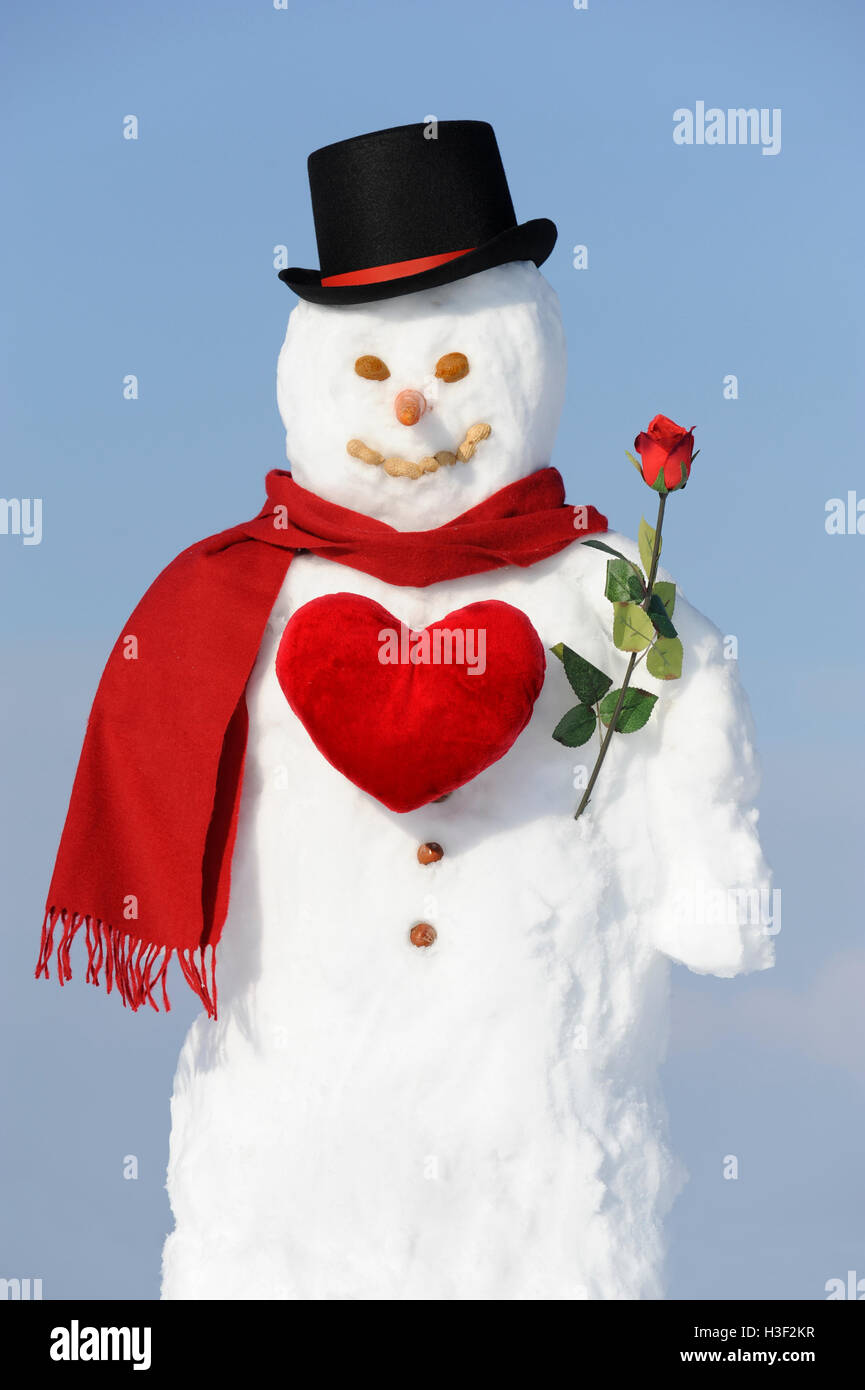 Schneemann mit rotem Herz und Rose als Symbol für die Liebe Stockfoto