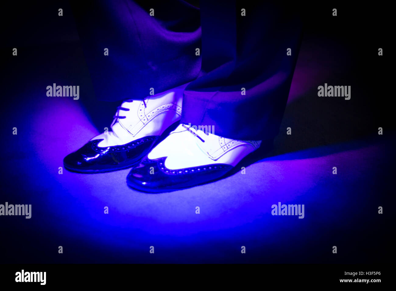 Latein und Salsa Tänzer im schwarzen und weißen Jazz Tanzschuhe in hellen und dunklen blau leuchtet auf der Bühne. Stockfoto