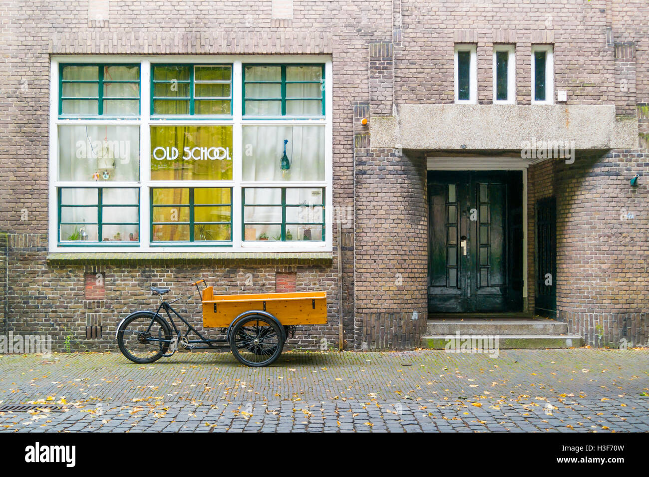 Lastenfahrrad parkte vor alten Schulgebäude in der Innenstadt von Leiden, Südholland, Niederlande Stockfoto