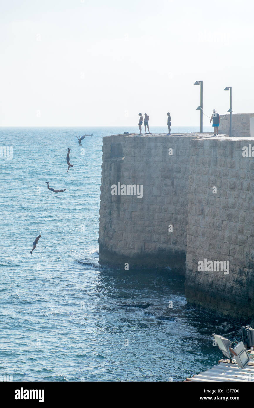 ACRE, ISRAEL - 3. August 2016: Junger Mann springt auf das Meer von der Spitze der alten Stadtmauer von Akko, Israel. Eine Kombination von m Stockfoto