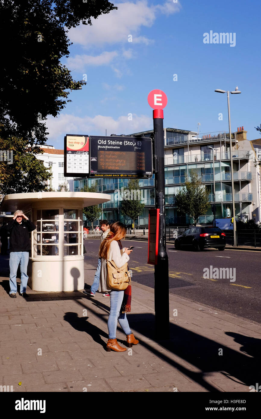 Junge Frau, die Überprüfung der Buszeiten auf ihrem Handy an Bushaltestelle in alten Steine Brighton UK Stockfoto Junge Frau, die Überprüfung der Buszeiten auf ihrem Handy an Bushaltestelle in alten Steine Brighton UK Stockfoto