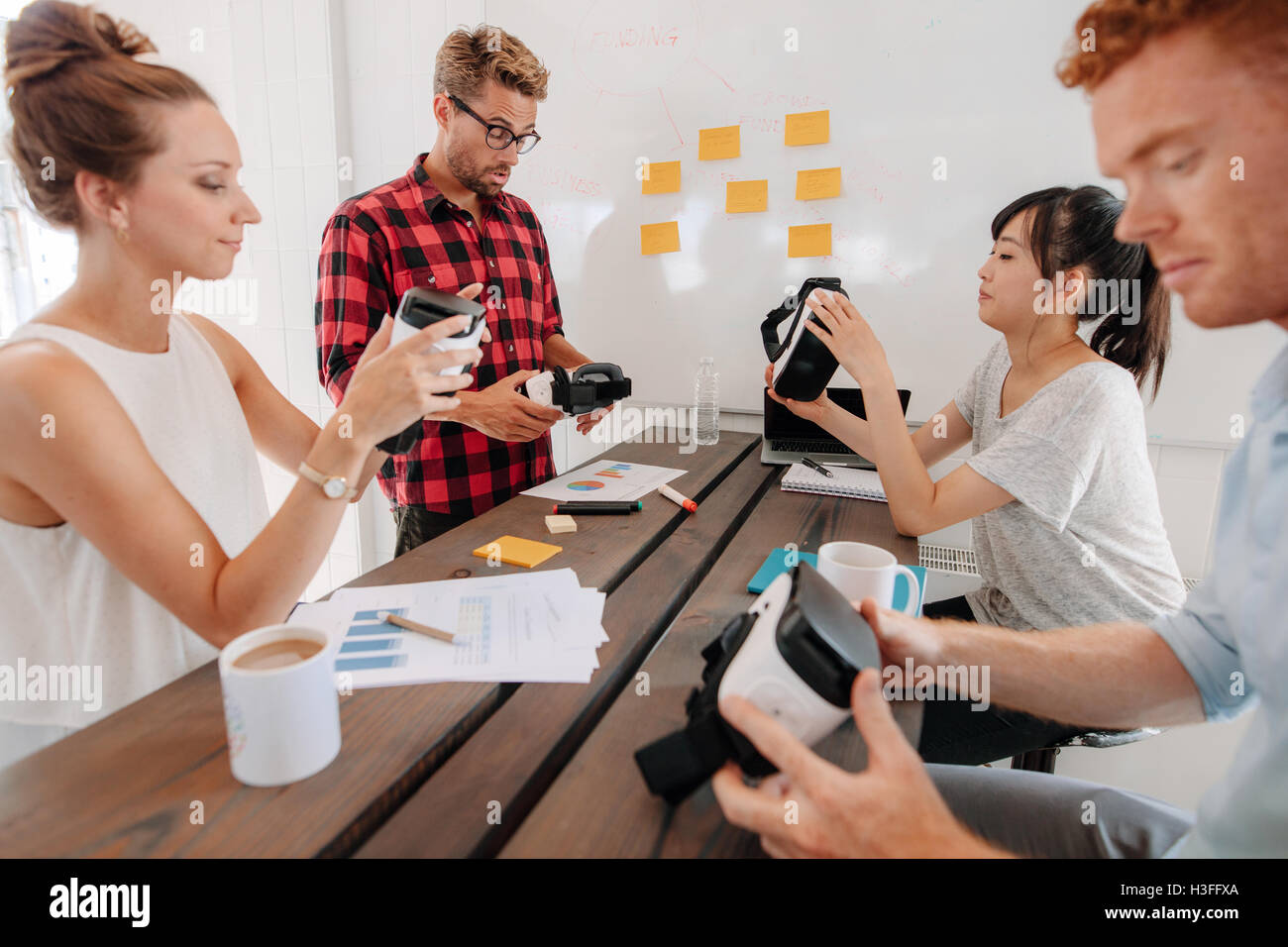 Gruppe von jungen Entwicklern arbeitet an der Verbesserung augmented Reality-Geräte. Verschiedene Business-Team im Tagungsraum betrachten virtu Stockfoto