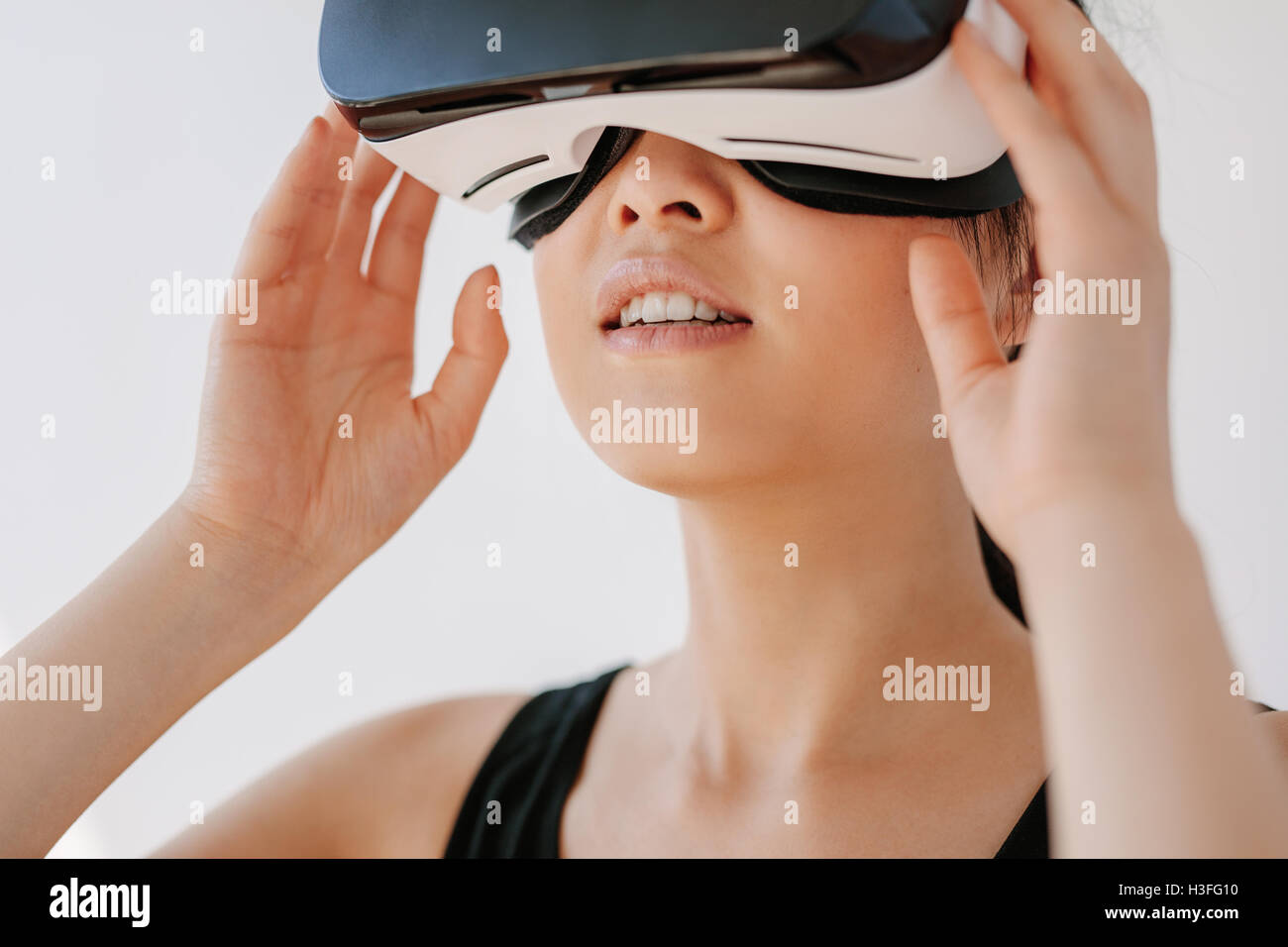 Nahaufnahme der glückliche junge Frau mit der VR-Brille vor grauem Hintergrund. Asiatische weibliche Modell VR Kopfhörer tragen. Stockfoto