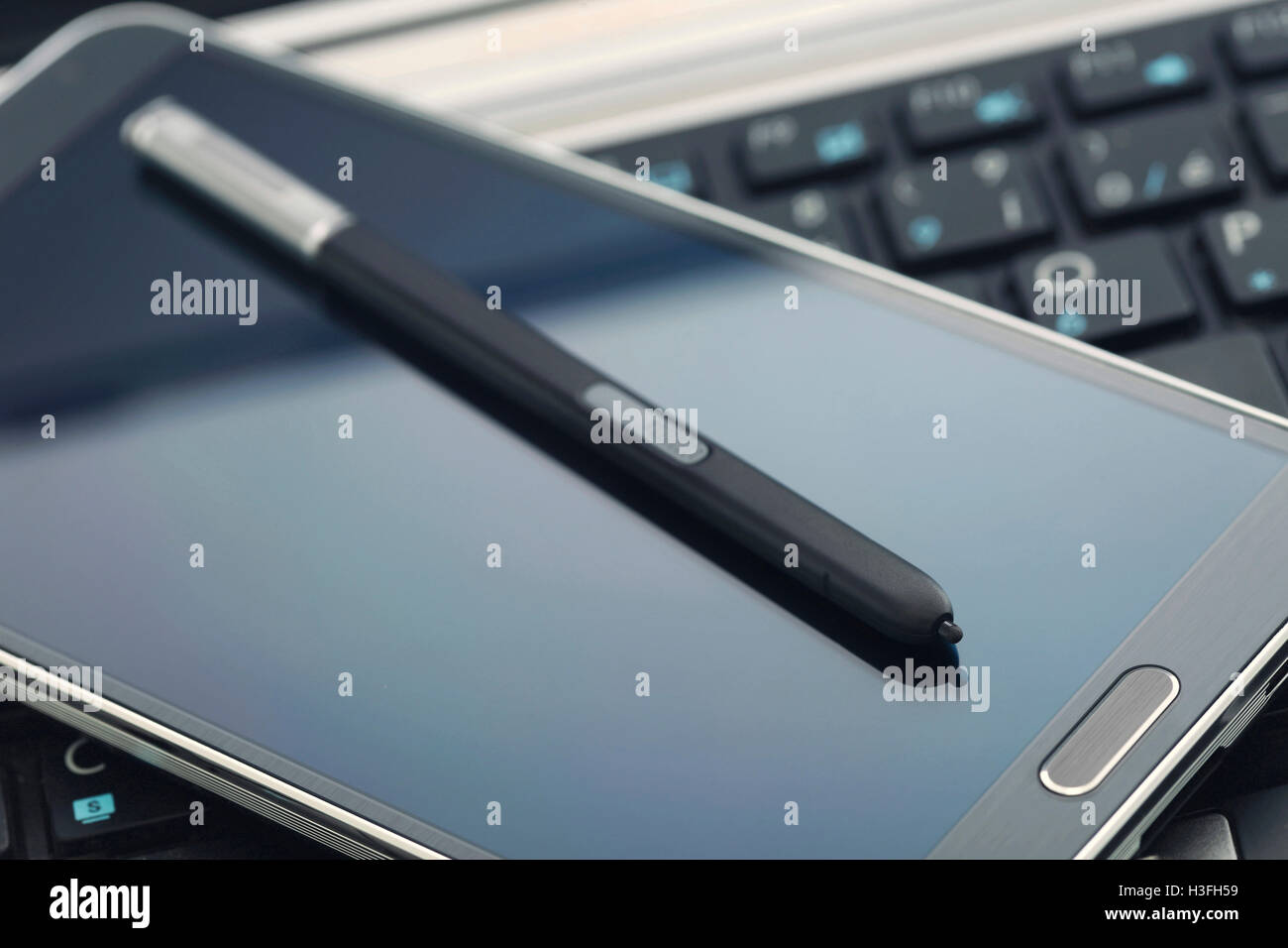 Phablet mit Stift auf Laptop-Tastatur. Stockfoto