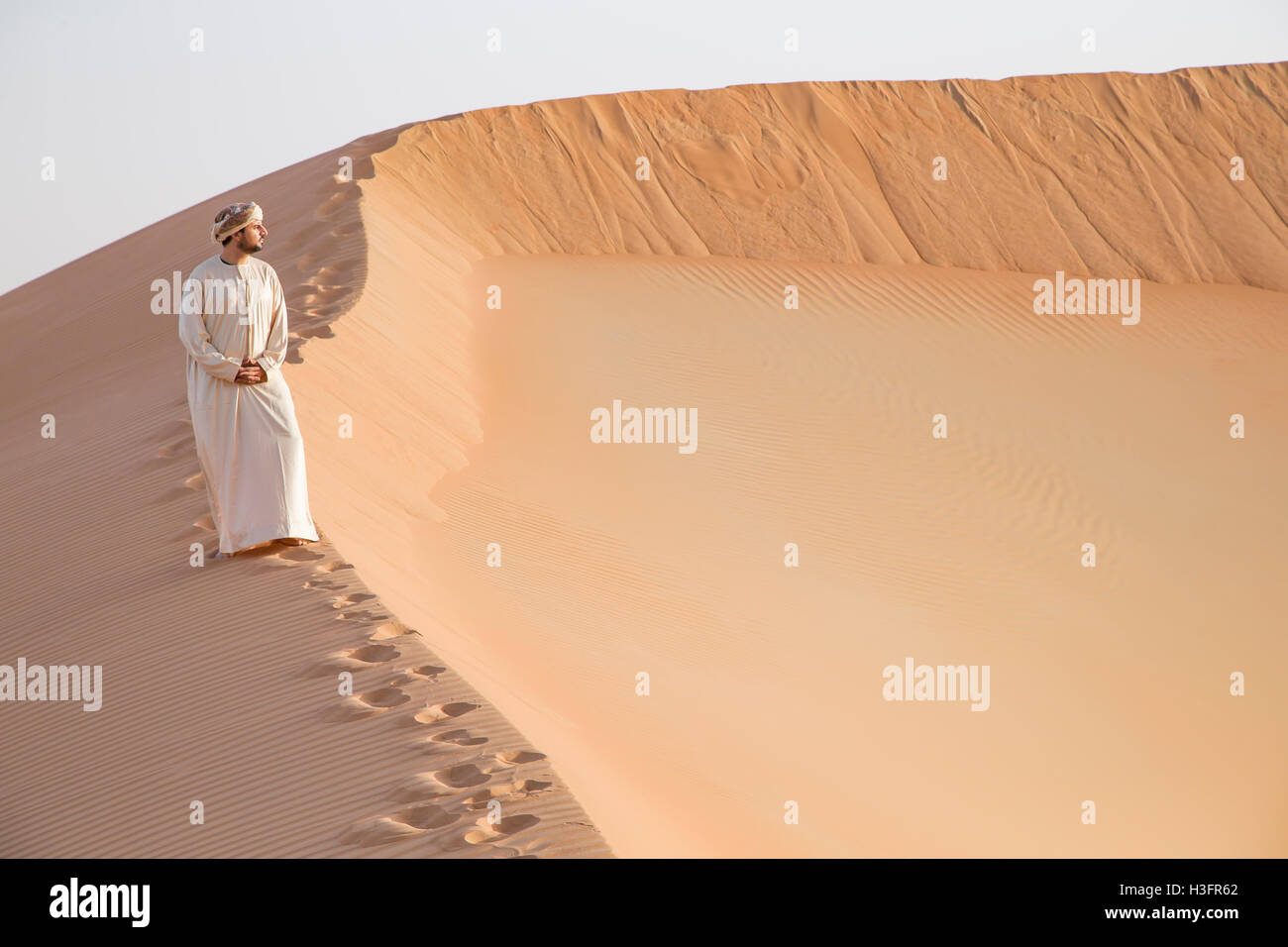 Mann in traditioneller Kleidung in einer Wüste bei Sonnenaufgang Stockfoto