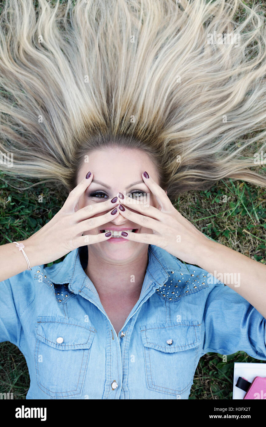 Schöne junge blonde liegen auf dem Rasen und unter selfie Stockfoto
